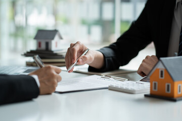 A real estate agent or bank officer explains the interest on a loan to customers with a home sales contract or office loan. Salesperson recommends insurance for customers who buy model homes.