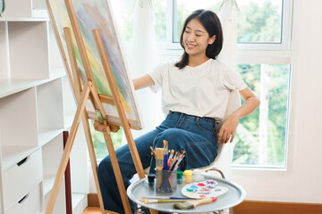 The art concept, Asian female artist use paintbrush to drawing artwork on canvas in art studio