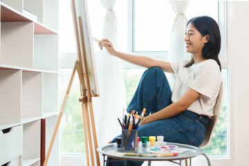 The art concept, Asian female artist using paint brush to painting for create artwork on canvas