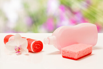 Bottle of dishwashing liquid, garbge bags and sponge on blurred background.