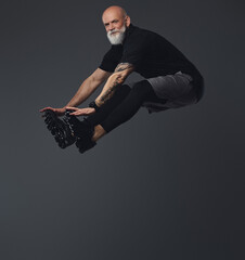 Portrait of carefree senior athlete man dressed in sportswear jumping looking at camera.
