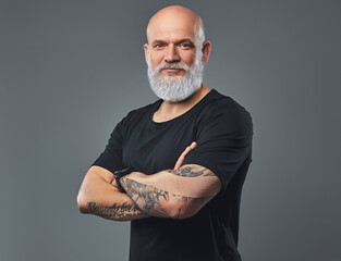 Shot of bald elderly sportsman with tattooed hands and long beard looking at camera.