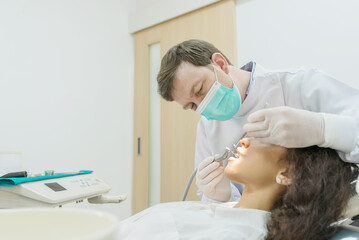 Caucasian male dentist examining young girl patient teeth at dental clinic. 