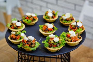 Selective focus. Serving tartlets with eggplant salad and mozzarella on a round stand.