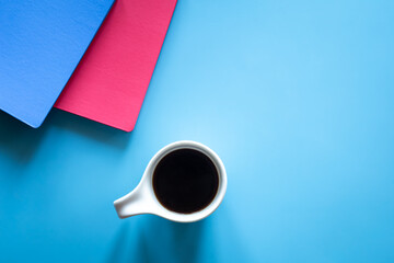 A cup of coffee and notepads on a blue background, minimalism.