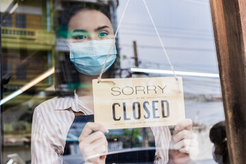 Caucasian coffee owner wear mask due pandemic, turns sorry closed sign. Attractive young girl...