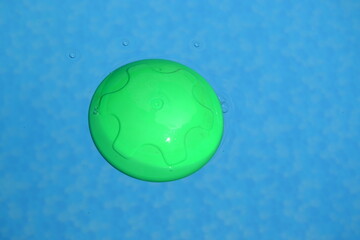 A floating chlorine tablet dispenser for swimming pools lies in the water.