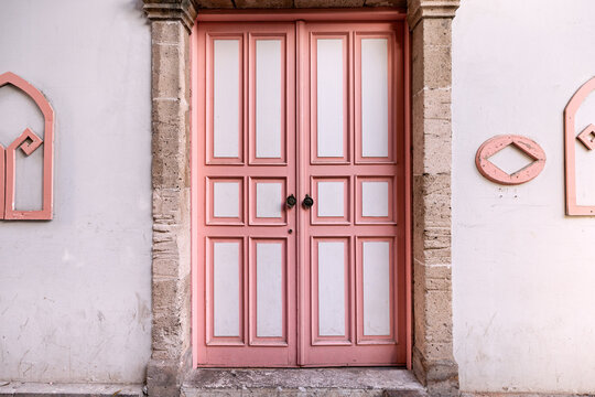 vintage wooden door painted in white and pink in the old town.