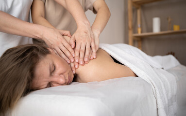 Woman having four hands massage, female hands massaging girl's shoulders, relaxing massage training, masseur work concept
