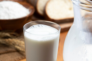 木のテーブルにグラスにはいった牛乳とたくさんのパン