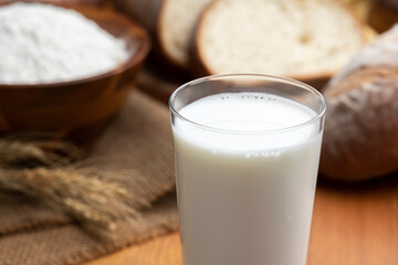 木のテーブルにグラスにはいった牛乳とたくさんのパン
