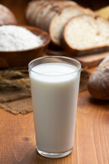 木のテーブルにグラスにはいった牛乳とたくさんのパン