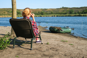 Fototapeta premium Blonde woman in cozy blanket enjoying hot drink in the morning near river