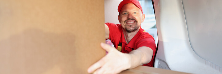 Man enjoying working in delivery company, put boxes in truck for further delivery on address
