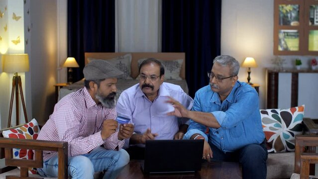 A bearded man is helping his two friends to enter debit /  credit card details - online shopping  e-commerce website. Three old friends using a laptop for making online payments - cashless transact...