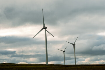 Fototapeta premium Wind turbine in a big open field. County Galway, Ireland. Production of clean electric energy. Dark dramatic sky. Nobody. Green renewable source of power.