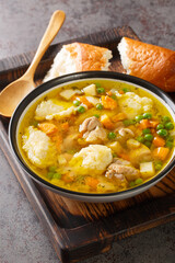 Eingemachtes Chicken Soup with Wheat Grits Dumplings close-up in a bowl on the table. Vertical