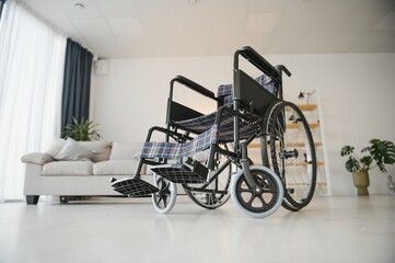 Fototapeta na wymiar Empty wheelchair in the livingroom. Lonely and healthcare concept.