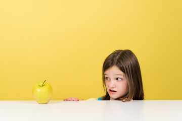 Little girl rejecting fruit isolated on yellow background. Healthy eating  on childhood concept - obrazy, fototapety, plakaty