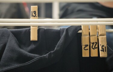 Nummerierte Wäscheklammern aus Holz an weißem Wäscheständer mit schwarzer Kutte