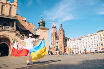 woman with ukrainian and poland flag at Krakow city center square