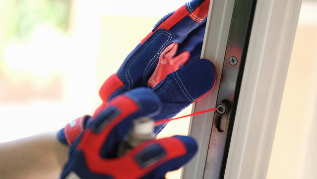 Repairman using lubricate for fix up problem with lock of plastic window.