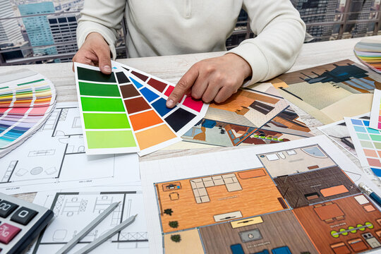 male  in the office selects a palette of colors for drawings of the house on the project.