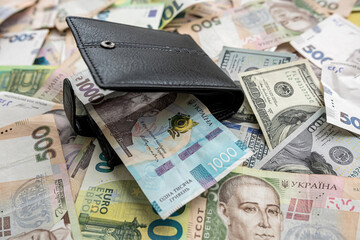 many euro hryvnia banknotes lie on the table next to a wallet with money and a calculator table