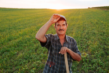 glad Latin American farmer with cap looking at the camera cheerfully and smiling at sundown.