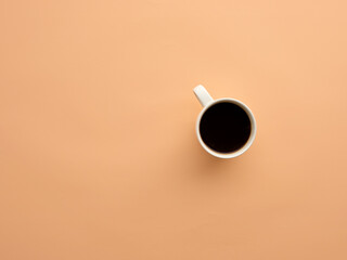 Coffee mug with black coffee on salmon colored background