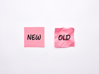 The words old and new on pink sheets of note paper on white background.