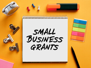 The word small business grants written on a notebook on business desktop