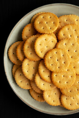 Salty Round Crackers on a Plate on a black surface, top view. Flat lay, overhead, from above.