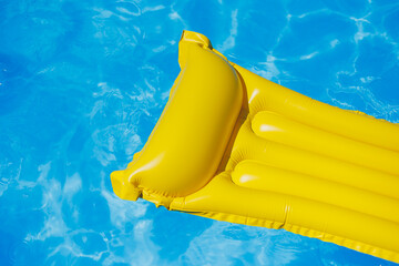 A yellow air mattress floats in an empty pool of blue water. Summer holiday concept