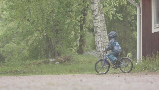 EXTREME WEATHER, SLOMO - A child rides their bike through the heavy rain