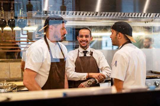 Smiling chef standing with colleagues seen through glass