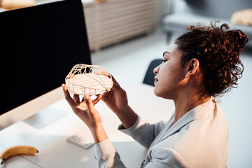Businesswoman examining architectural model at office