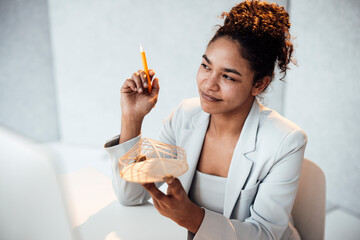 Smiling businesswoman with architectural model sitting at desk