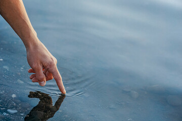 Hand of mature man touching water