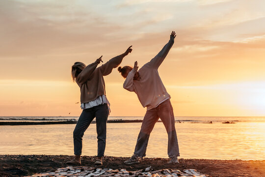 Teenage girl with mother doing dab standing at beach