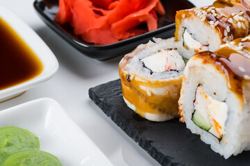 close-up, on a white table and a black stand, Japanese rolls with eel, cream cheese and teriyaki...