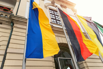 Big Ukraine Germany and Saxony Anhalt flags waving blowing by wing on Magdeburg city hall building facade. Ukrainian and Germany partnership, support and friendship concept - obrazy, fototapety, plakaty