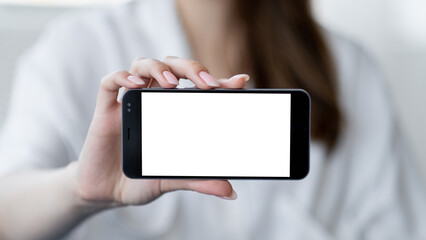 Virtual life. Digital mockup. Mobile connection. Unrecognizable defocused woman holding smartphone with blank screen in light room interior.