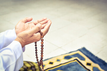 Muslim man in white session lift two hand for praying and wearing bead on hand to determine the number of prayer services.concept for Ramadan, Eid al Fitr, eid ad-ha, meditation, islamic praying