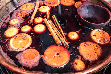 Bowl of traditional English hot spicy mulled wine with cloves, cinnamon sticks, dried fruit and red...