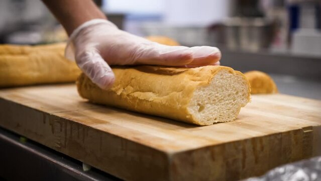 Chef slices french bread baguette, slow motion close up 4K