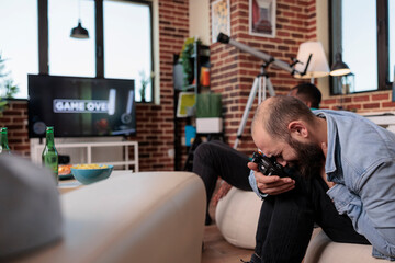 Fototapeta premium Caucasian man losing at shooting video games strategy, feeling frustrated and angry about lost competition game. Sad person being irritated after shooter gaming lose at gathering with friends.