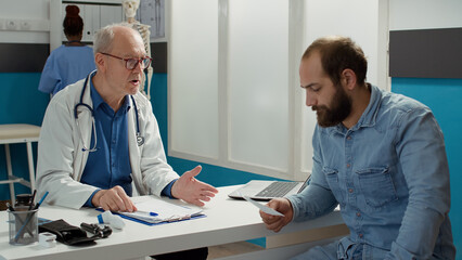 Male physician giving prescription paper to sick person at checkup visit appointment in office. Examination report with health care information and disease diagnosis, treatment to cure illness.