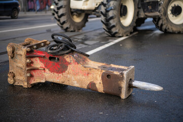 Hydraulic jackhammer from excavator construction truck isolated on busy asphalt road. Construction works and repairs.