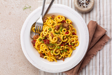 Italian meat pasta Gramigna with salsiccia, green peas and sun dried tomatoes. Directly above.